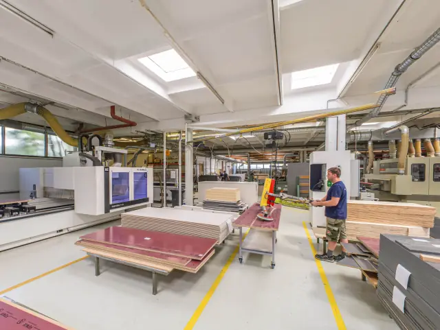 Maschinenhalle einer Möbelwerkstätte mit Plattenlager, Kreissäge und CNC-Anlage